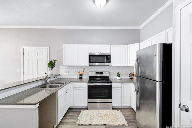 kitchen with appliances with stainless steel finishes, sink, crown molding, dark hardwood / wood-style floors, and white cabinetry