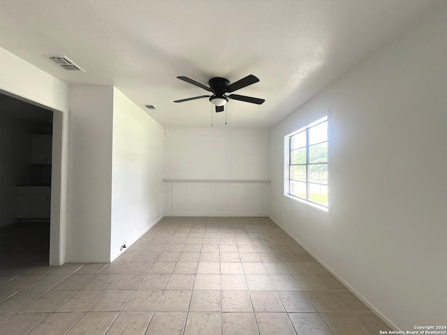 tiled spare room featuring ceiling fan