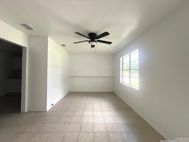 spare room with a ceiling fan, visible vents, and light tile patterned floors