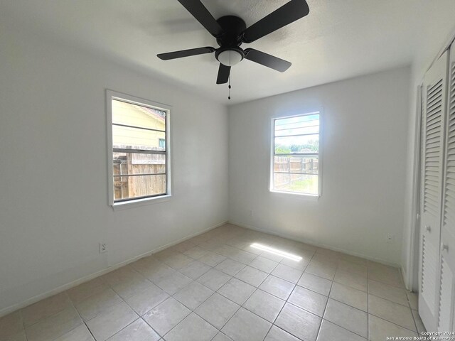 unfurnished bedroom with a closet, light tile patterned floors, and ceiling fan