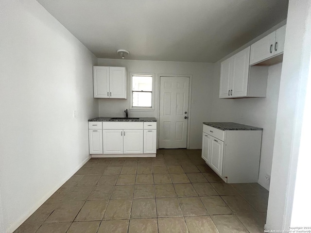2205 Louise St, Seguin, TX 78155 - kitchen with dark countertops, white cabinets, a sink, and light tile patterned floors