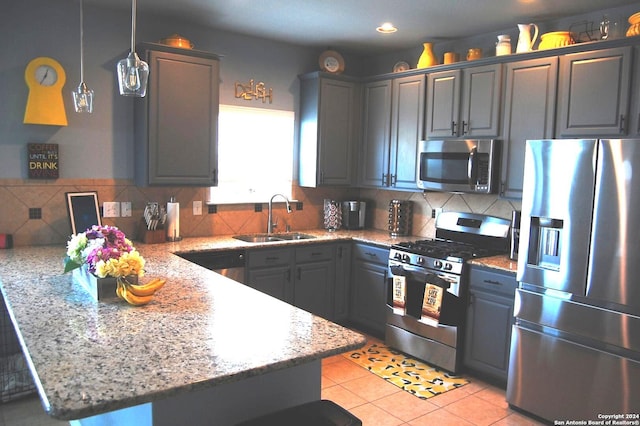 kitchen with sink, hanging light fixtures, decorative backsplash, stainless steel appliances, and light stone countertops