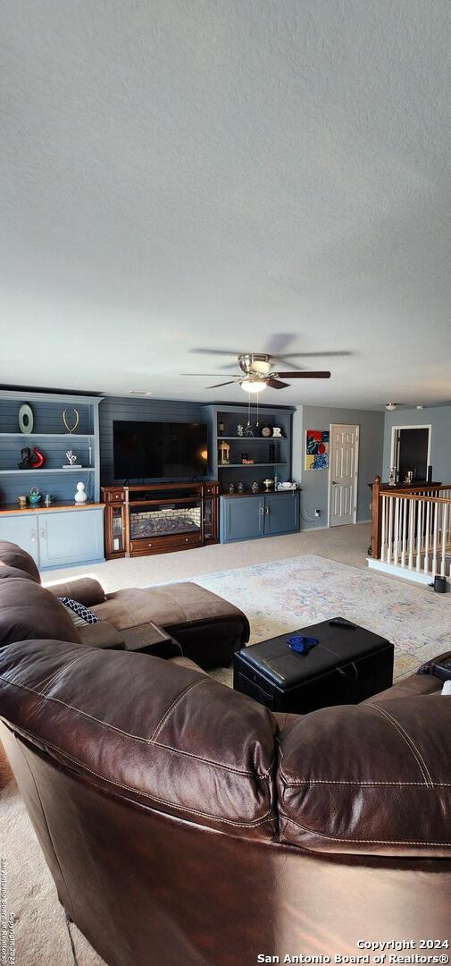 carpeted living room with a textured ceiling and ceiling fan