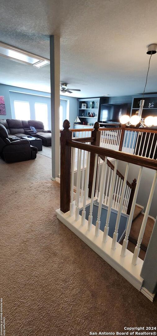 stairs with carpet floors, a textured ceiling, and ceiling fan