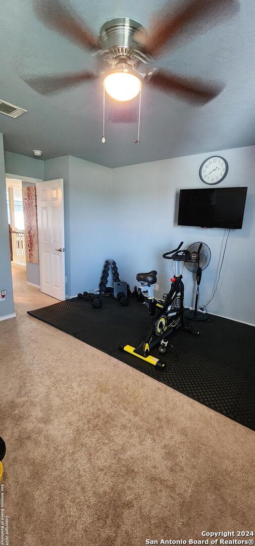 workout room with a textured ceiling, carpet, and ceiling fan