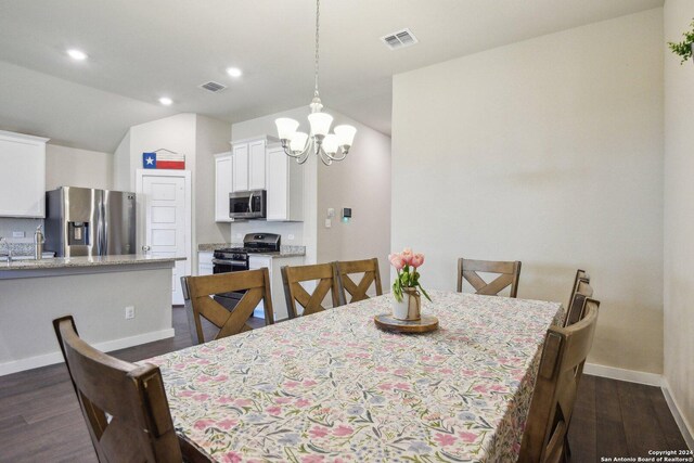 dining area featuring sink, dark hardwood / wood-style flooring, an inviting chandelier, and lofted ceiling