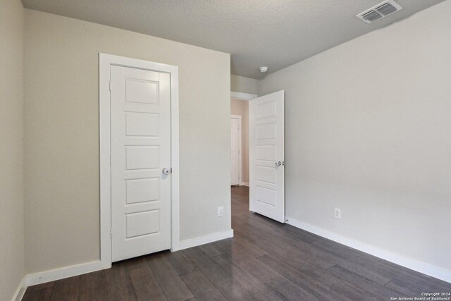 unfurnished bedroom with dark hardwood / wood-style floors and a textured ceiling