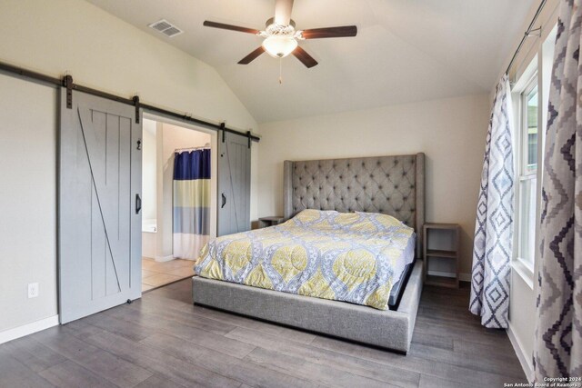 bedroom featuring a barn door, hardwood / wood-style flooring, vaulted ceiling, and ceiling fan