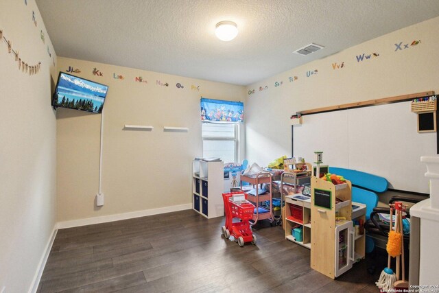 game room featuring a textured ceiling and dark wood-type flooring