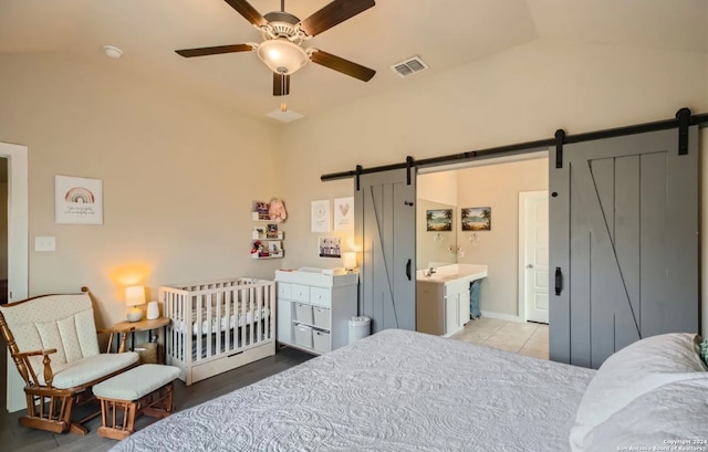 bedroom featuring a barn door, connected bathroom, ceiling fan, and high vaulted ceiling