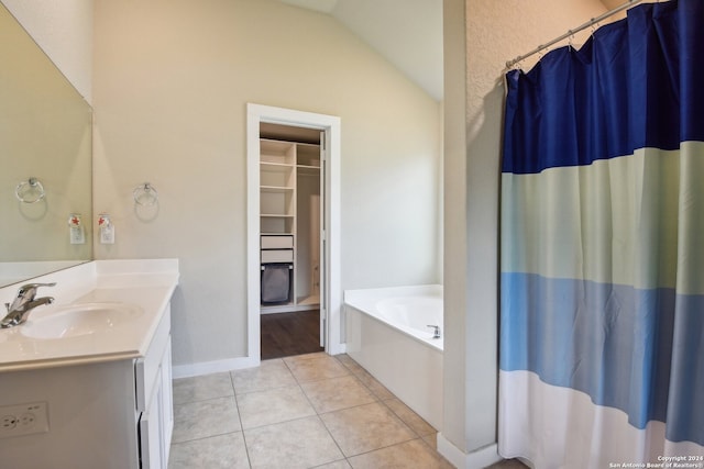 bathroom with tile patterned flooring, lofted ceiling, a washtub, and vanity