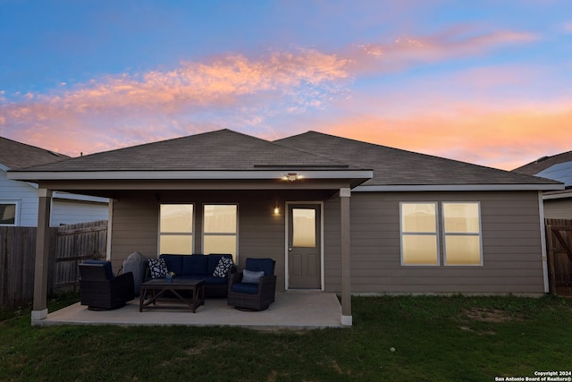 back house at dusk with an outdoor hangout area, a lawn, and a patio area