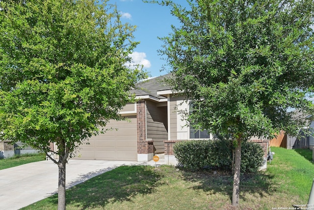 view of property hidden behind natural elements featuring a garage and a front lawn