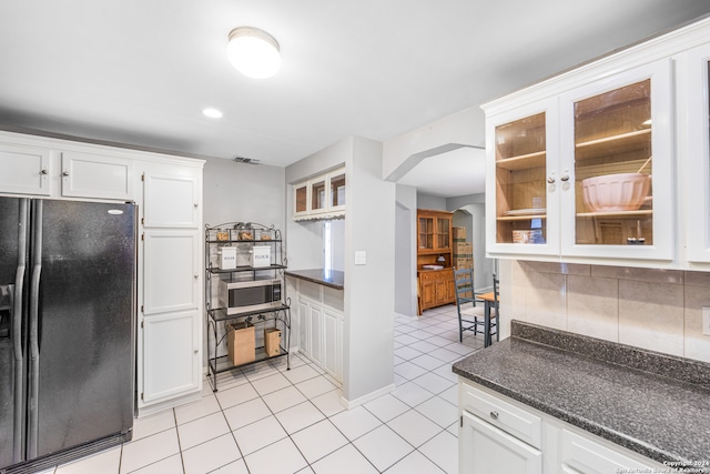 kitchen featuring white cabinets, black fridge, and light tile patterned floors