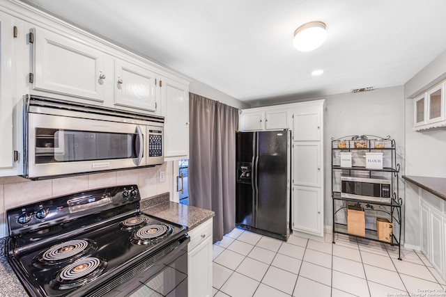 kitchen featuring white cabinetry, light tile patterned floors, dark stone counters, backsplash, and black appliances