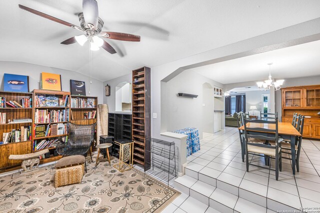 tiled living room featuring ceiling fan with notable chandelier and vaulted ceiling