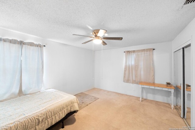 carpeted bedroom featuring a textured ceiling, ceiling fan, and a closet