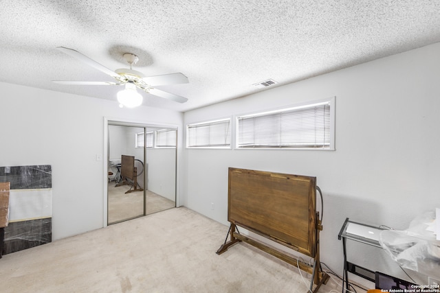 bedroom with light colored carpet, a closet, a textured ceiling, and ceiling fan