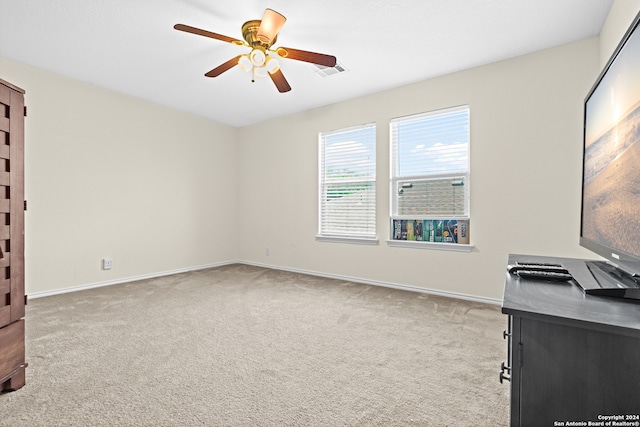 unfurnished office featuring light carpet and ceiling fan