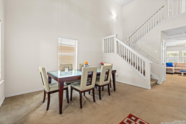 dining space featuring a high ceiling and light colored carpet