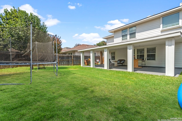 exterior space featuring a patio, a trampoline, and a yard