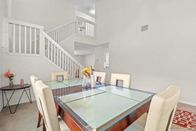 carpeted dining area featuring a towering ceiling