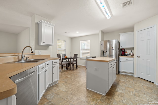 kitchen featuring white cabinets, light tile patterned floors, appliances with stainless steel finishes, and sink