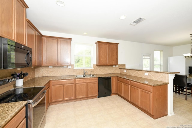 kitchen with sink, light stone counters, decorative light fixtures, black appliances, and kitchen peninsula