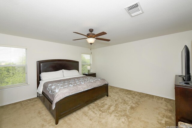 bedroom with light carpet, multiple windows, and ceiling fan