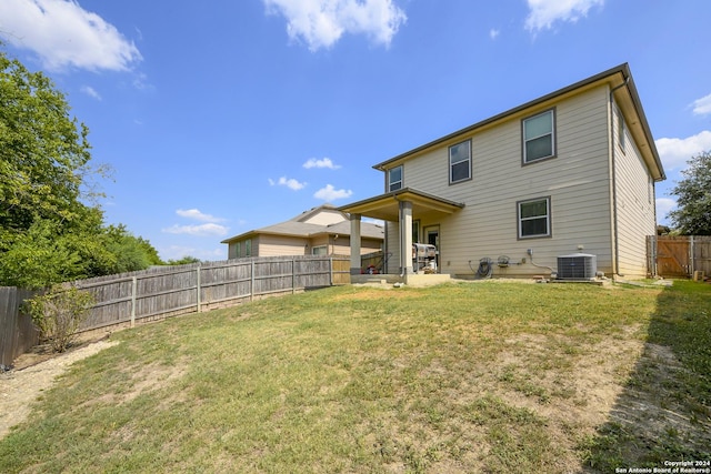 rear view of house with cooling unit, a yard, and a patio area