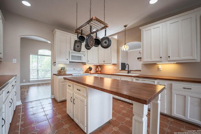 kitchen featuring white cabinetry, white appliances, a kitchen island, dark hardwood / wood-style floors, and butcher block countertops