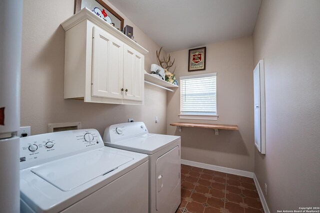 washroom with cabinets, washer and dryer, and dark tile patterned flooring