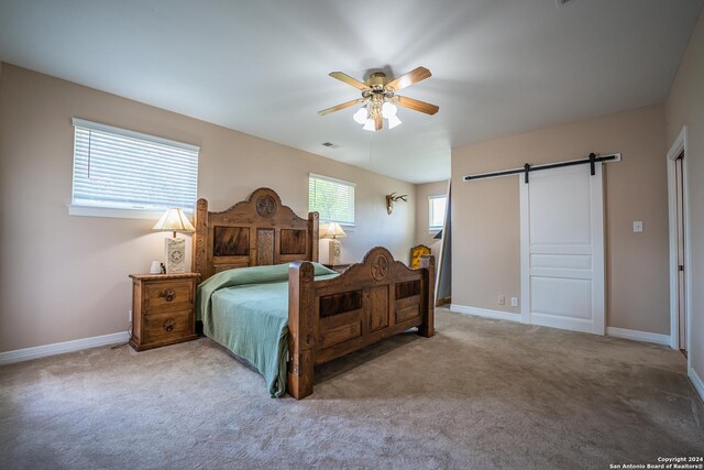 carpeted bedroom featuring a barn door and ceiling fan