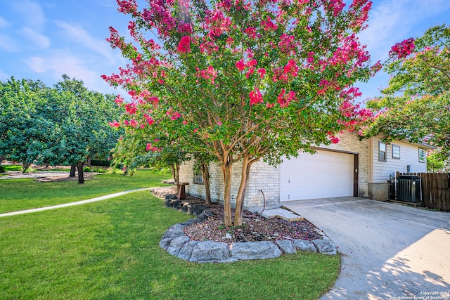 view of front of property featuring cooling unit, a garage, and a front yard