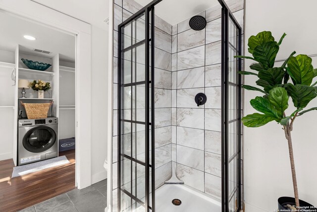 bathroom featuring washer / dryer, hardwood / wood-style floors, and an enclosed shower