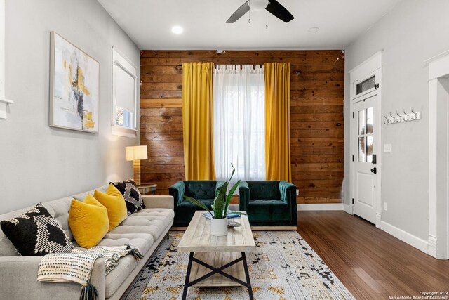 living room featuring wooden walls, hardwood / wood-style floors, and ceiling fan