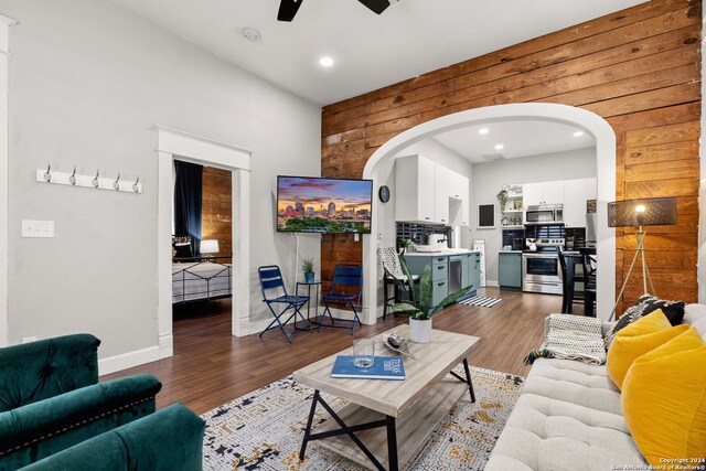 living room featuring wood walls, ceiling fan, and dark hardwood / wood-style floors