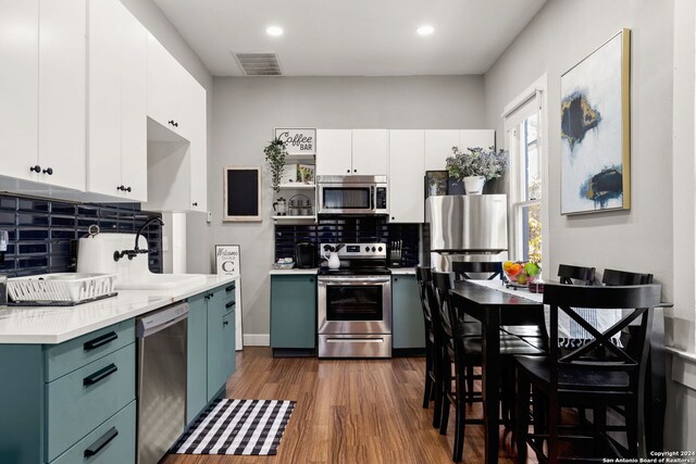 kitchen with appliances with stainless steel finishes, tasteful backsplash, white cabinets, sink, and dark wood-type flooring