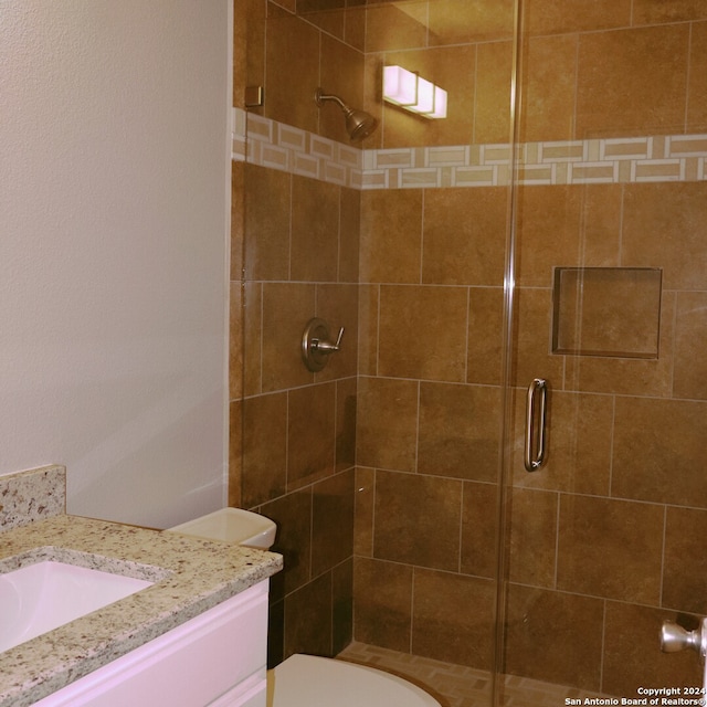 bathroom with vanity, toilet, and a shower with door