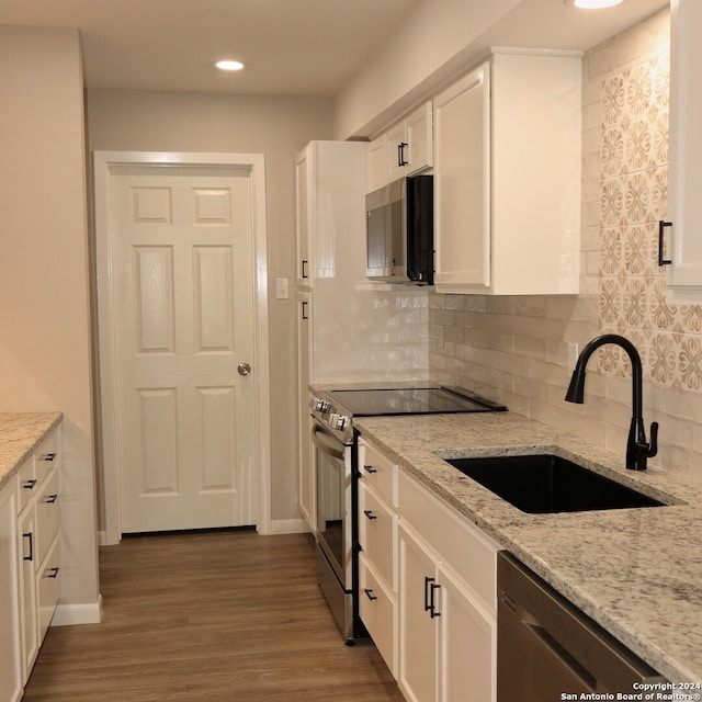 kitchen with hardwood / wood-style floors, sink, light stone countertops, appliances with stainless steel finishes, and white cabinets