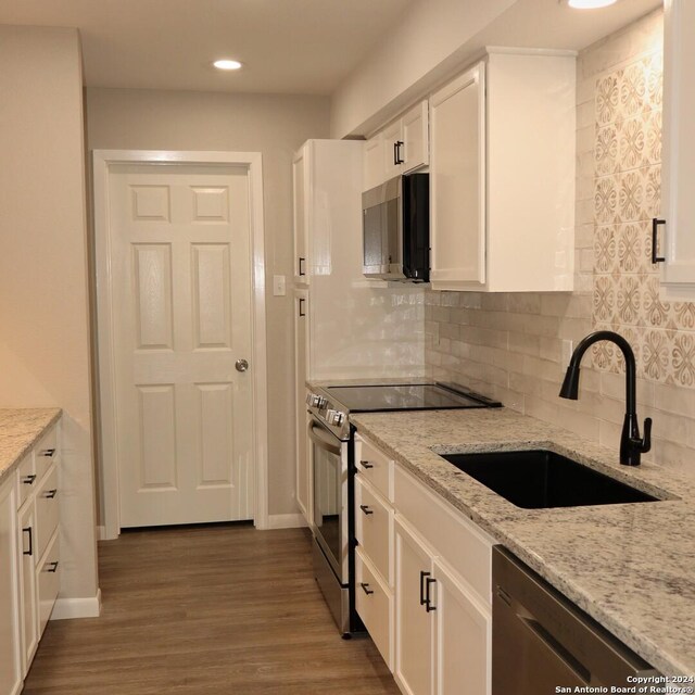 kitchen featuring light stone countertops, appliances with stainless steel finishes, backsplash, and white cabinetry