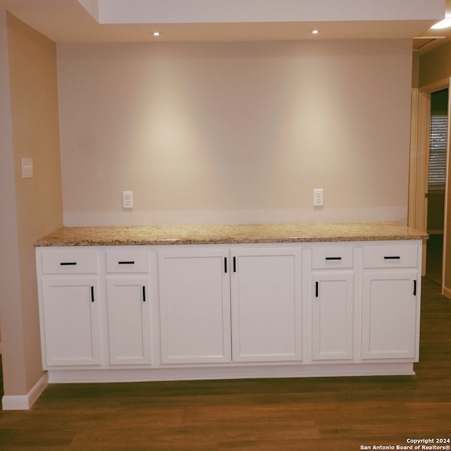 interior space with dark hardwood / wood-style flooring, light stone counters, and white cabinets