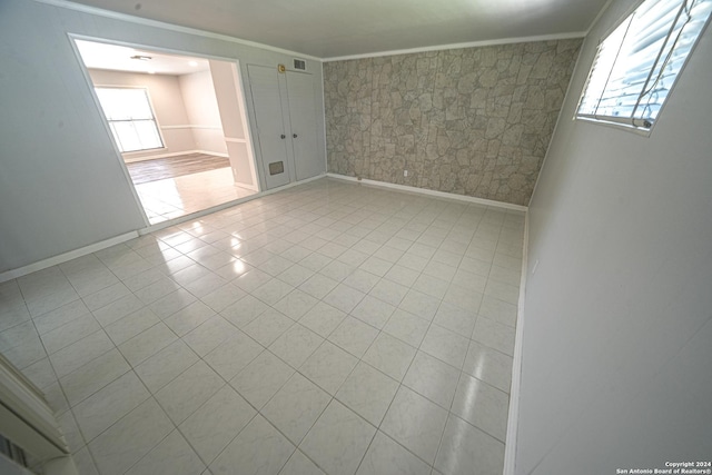 tiled spare room featuring ornamental molding