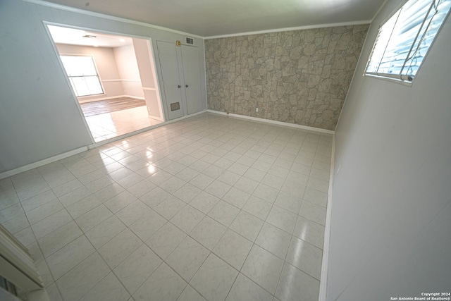 spare room featuring light tile patterned flooring and ornamental molding