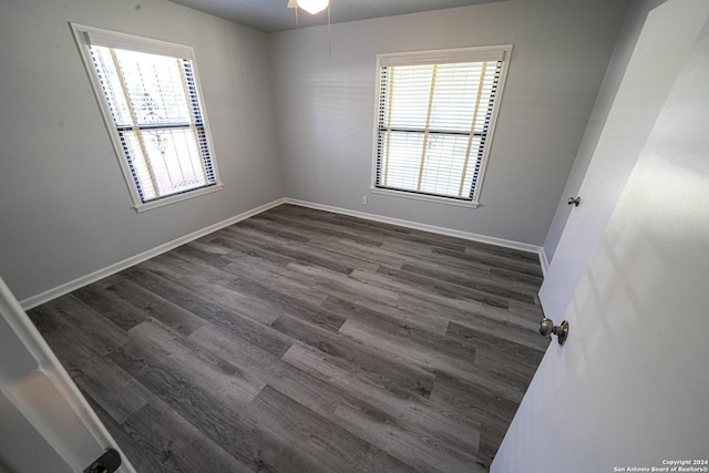 empty room with dark hardwood / wood-style floors and a healthy amount of sunlight