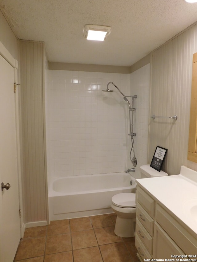 full bathroom featuring a textured ceiling, toilet, vanity, tiled shower / bath combo, and tile patterned flooring