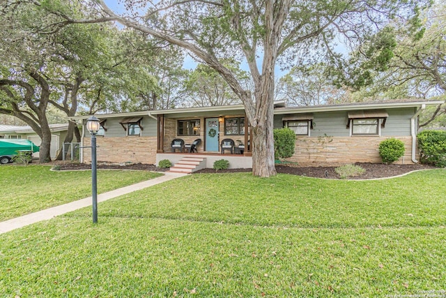 single story home featuring stone siding, a porch, and a front yard