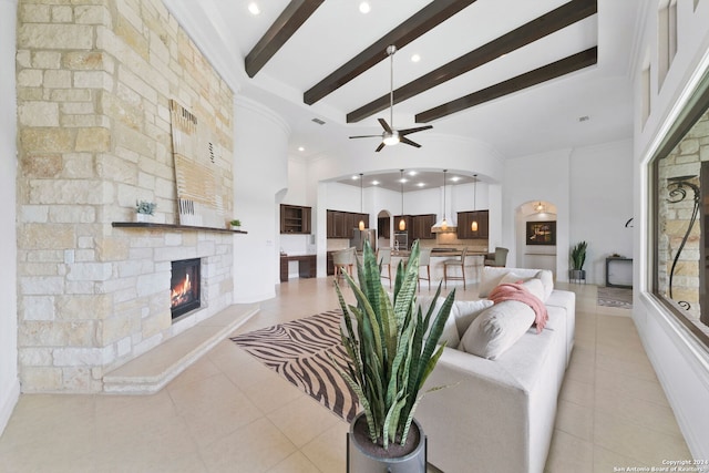 tiled living room with ornamental molding, a fireplace, ceiling fan, and beam ceiling