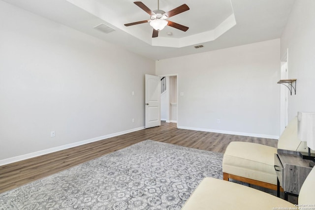 sitting room featuring wood-type flooring, ceiling fan, and a tray ceiling