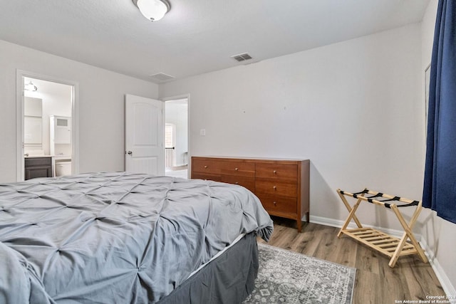 bedroom with hardwood / wood-style flooring and connected bathroom